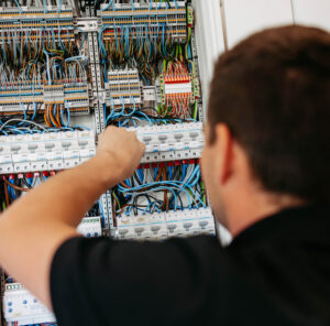 Ein Elektriker arbeitet an einem Schaltschrank, um Elektroinstallation zu installieren.