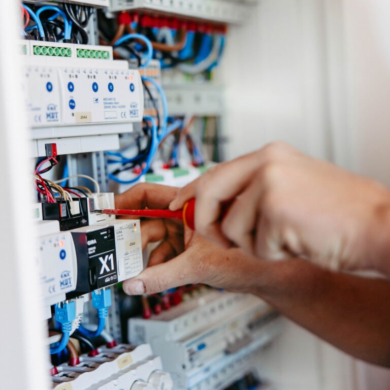 Ein Elektriker der Elektrotechnik Hönnetal schraubt an einer Stromverteilung.